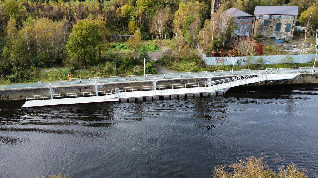 Bridge pontoon on river's edge with greenery in the background