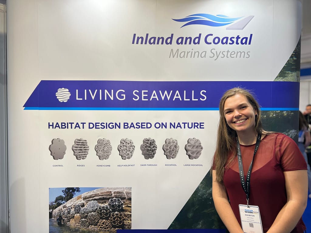 Jess Allen in front of Living Seawalls poster at Inland and Coastal stand SIBS 2024